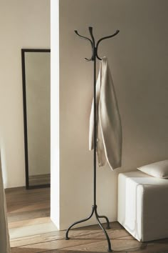 a coat rack with a white cloth hanging from it's side and a mirror in the background