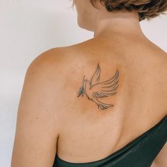 the back of a woman's shoulder with a bird tattoo on it