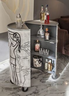 a bar cart with liquor bottles on it in the middle of a marble floored room