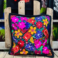 a colorful pillow sitting on top of a wooden chair