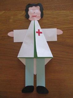 a paper doll with a red cross on it's chest and arms, standing in front of a wooden table