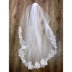 a white veil with lace on it sitting on top of a wooden floor