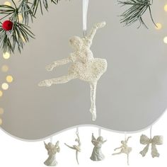 an ornament hanging from a christmas tree decorated with white ornaments and lights in the background