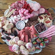 a platter filled with lots of different types of desserts and pastries on top of a wooden table