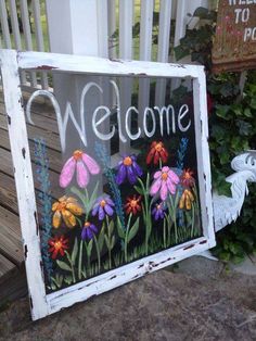 a sign with flowers painted on it that says welcome