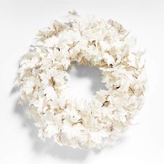 a wreath with white flowers hanging from it's side on a wall in front of a white background