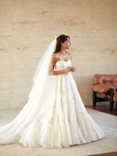 a woman in a white wedding dress standing on a rug and looking off to the side