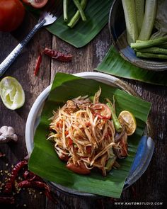 a plate filled with noodles and vegetables on top of a wooden table next to other foods