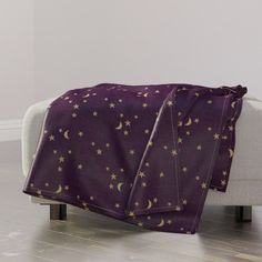 a purple blanket with gold stars and crescents on it sitting on a white couch