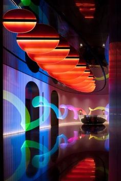 an art gallery with colorful lights and artwork on the walls, reflecting in the water