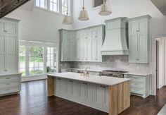 a large kitchen with white cabinets and wood flooring is pictured in this image, there are three pendant lights hanging from the ceiling