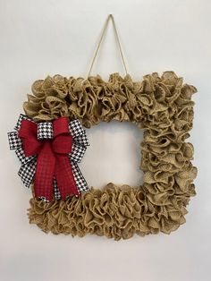 a burlap wreath with a red bow hangs on a wall in front of a white background