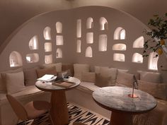 a living room filled with lots of furniture next to a wall covered in arched windows