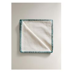 a white and blue dish towel on top of a square plate with green trimmings