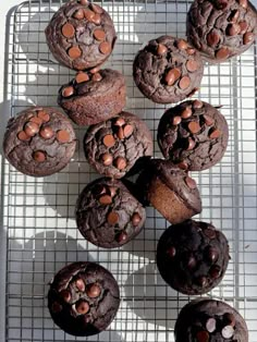 chocolate muffins cooling on a wire rack with chocolate chips in the middle and one half eaten