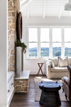 a living room filled with furniture and a stone fireplace mantel in front of a window