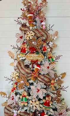 a decorated christmas tree with gingerbreads and other holiday decorations on it's top