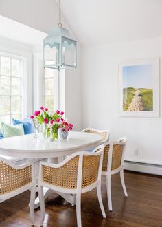 a dining room table with four chairs and a vase of flowers on top of it