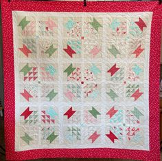 a red and white quilt hanging on a wall