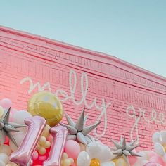 balloons and letters are arranged in front of a pink wall with the word hello written on it