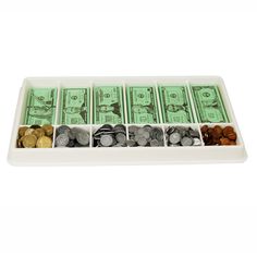 a tray filled with lots of money sitting on top of a white countertop next to each other