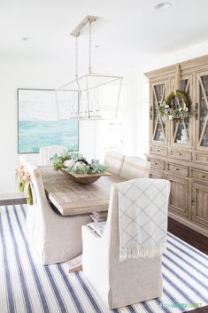 a dining room table with chairs and a striped rug on the floor in front of it