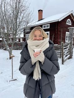 a woman standing in the snow with her scarf around her neck