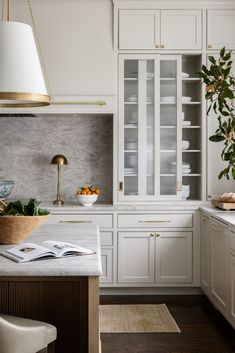 a kitchen with white cabinets and marble counter tops