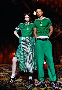 a man and woman in green outfits standing next to each other on a carpeted floor