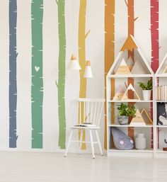 a room with colorful trees painted on the wall and a white chair next to it