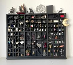 a shelf filled with lots of assorted items on top of a white table next to a wall