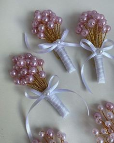 four hair pins with pink flowers and pearls on them, tied in white satin ribbons