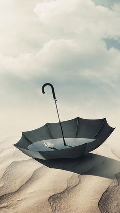 an umbrella floating in the air on top of sand dunes with a cloudy sky behind it