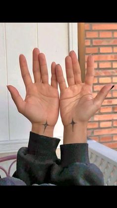 a woman with her hands in the air and two crosses tattooed on her left wrist