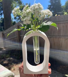 someone holding up a vase with flowers in it