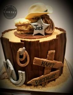 a birthday cake made to look like a log with cowboy hats and horseshoes on it