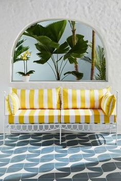 a yellow and white couch sitting in front of a mirror