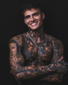 a man with tattoos on his chest and arms is smiling at the camera while posing for a photo