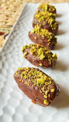 chocolate covered donuts with pistachio toppings on a white plate