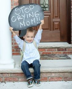 a little boy sitting on the steps holding up a sign