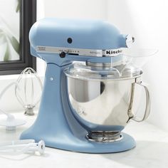 a blue kitchen mixer sitting on top of a counter next to a mirror and other appliances