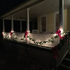 christmas lights are on the front porch of a house with wreaths and bows hanging from it