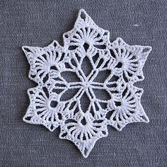 a white crocheted snowflake sitting on top of a gray table cloth