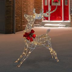 a lighted reindeer standing in front of a red door