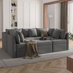 a living room with a large gray couch and wooden flooring in front of a sliding glass door