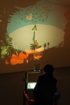 a person sitting at a desk in front of a projector screen with an image projected on it