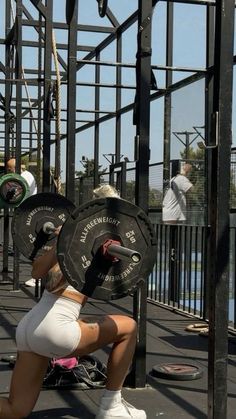 a woman squatting down with a barbell in her hand