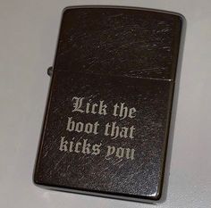 a black zippo with the words lick the boot that kicks you written on it