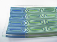 a blue and green glass plate sitting on top of a white tablecloth covered in circles