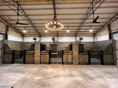 the inside of a horse barn with several stalls and lights hanging from the ceiling above